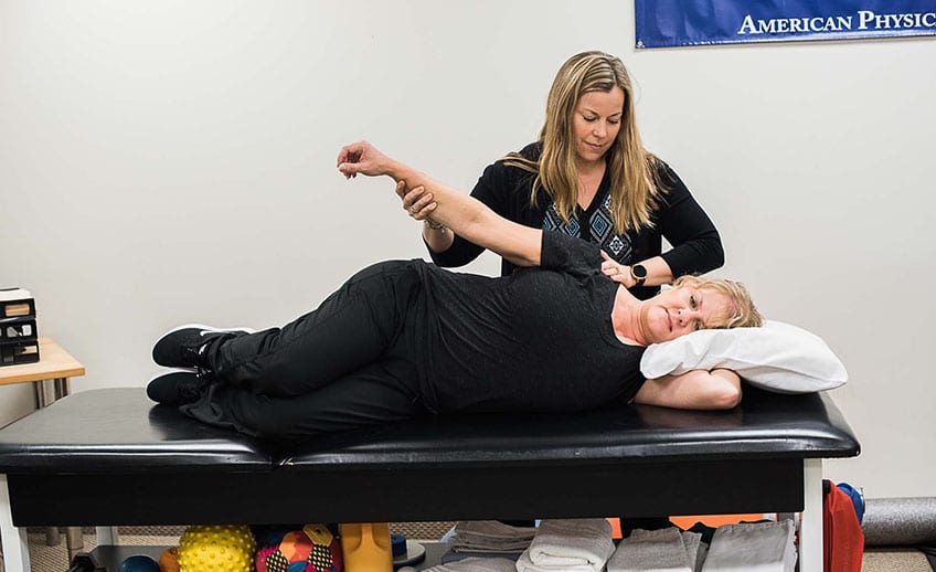 occupational therapist palpating shoulder during patient exercise
