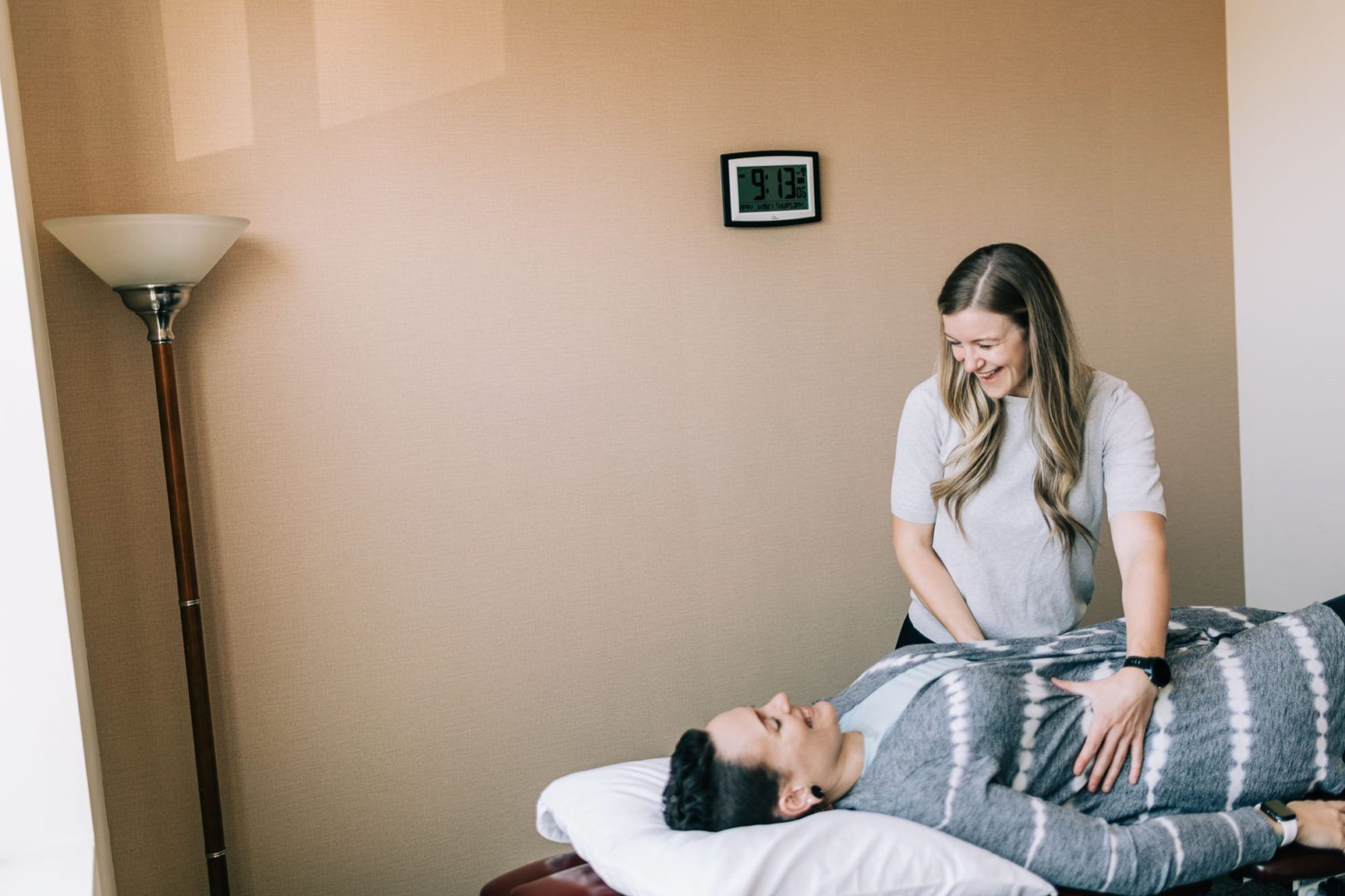 smiling physical therapist working with supine patient