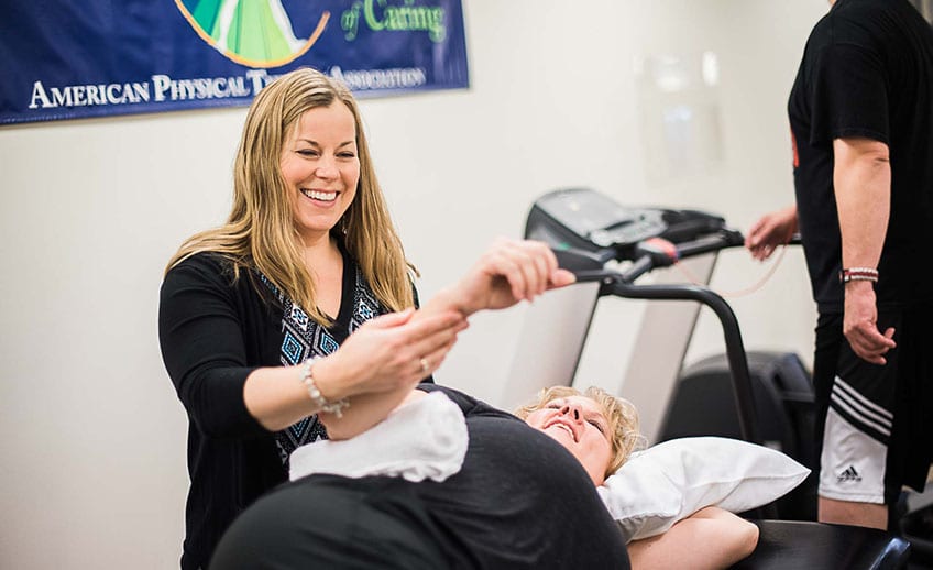 occupational therapist smiling while assisting shoulder exercise