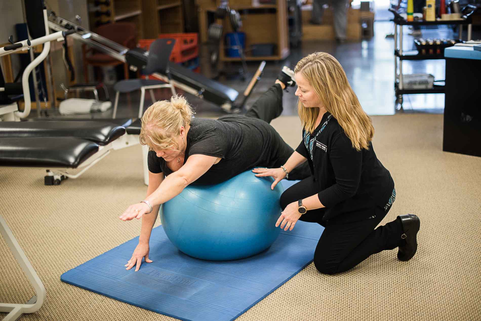 occupational therapist assists client with ball exercise in maple grove gym