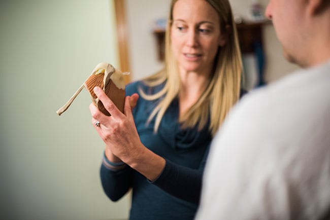 physical therapist educating patient with model of shoulder joint