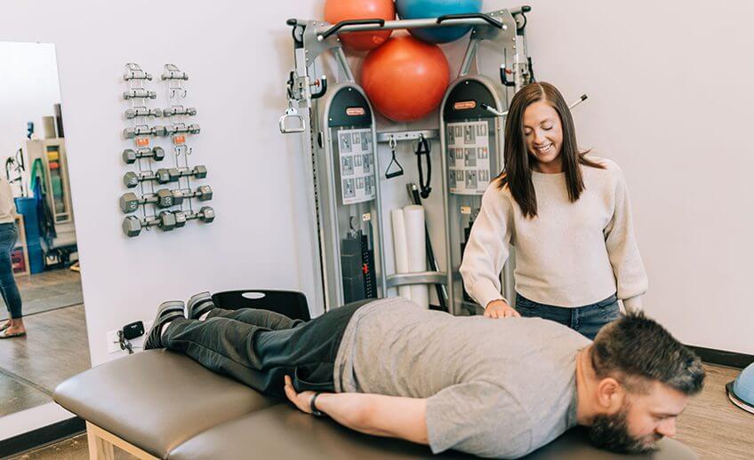 occupational therapist palpating upper back muscles during patient exercise
