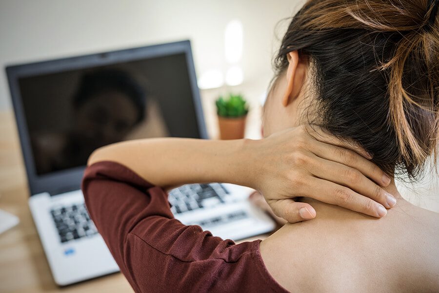 Woman working at computer rubbing her neck