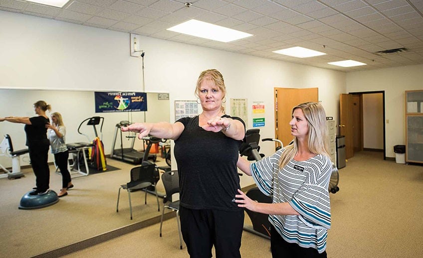 physical therapist helps client with balance exercises